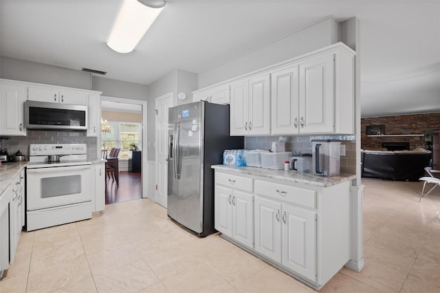 kitchen featuring decorative backsplash, white cabinets, and stainless steel appliances