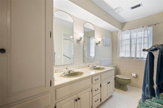 bathroom with vanity, toilet, tile patterned floors, and tile walls