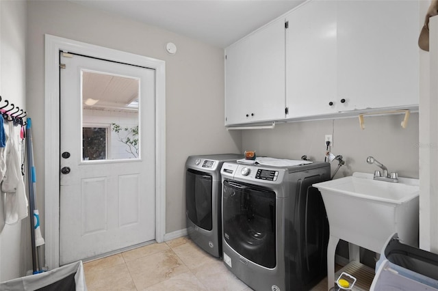 clothes washing area with sink, light tile patterned flooring, washer and dryer, and cabinets