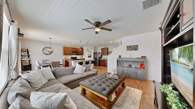 living room featuring ceiling fan, a textured ceiling, and light hardwood / wood-style flooring