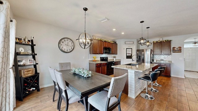 dining area with an inviting chandelier, light wood-type flooring, and sink