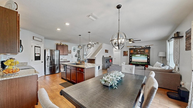 dining space featuring light hardwood / wood-style floors, a fireplace, ceiling fan, and sink