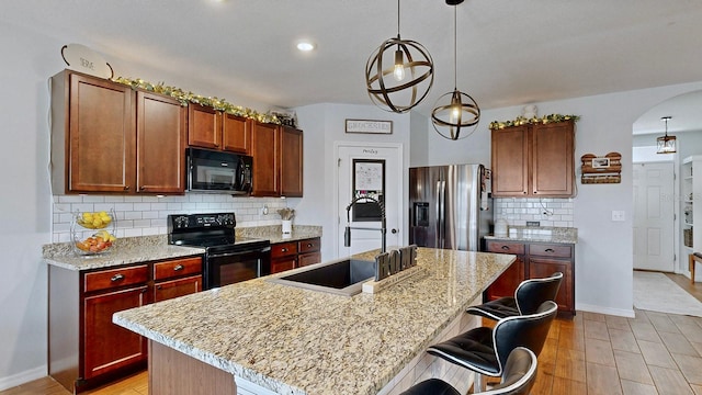 kitchen with pendant lighting, a kitchen island, sink, and black appliances