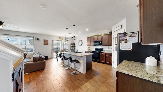 kitchen featuring light stone countertops, electric stove, ceiling fan, and a kitchen island