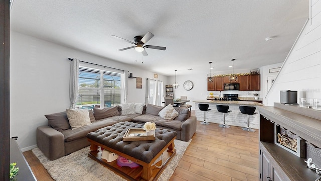 living room featuring light wood-type flooring, a textured ceiling, and ceiling fan