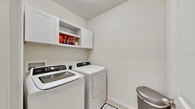 washroom with cabinets, a textured ceiling, and washing machine and clothes dryer