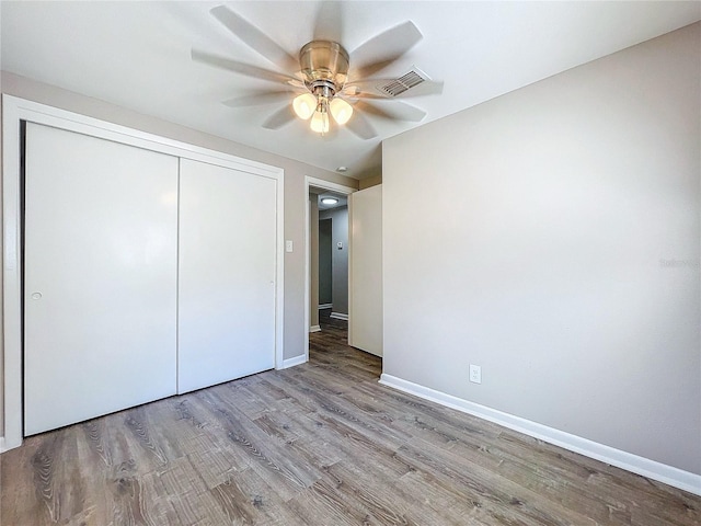 unfurnished bedroom with light wood-type flooring, ceiling fan, and a closet