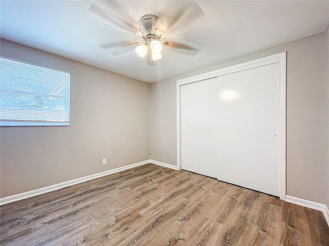 unfurnished bedroom featuring hardwood / wood-style floors, ceiling fan, and a closet