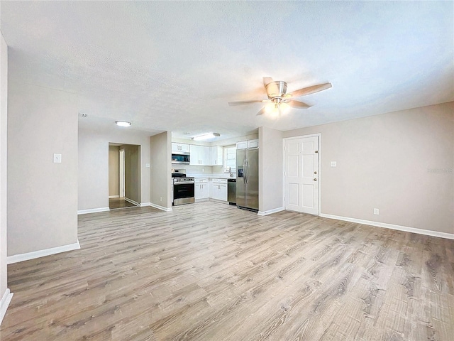 unfurnished living room featuring light hardwood / wood-style flooring, ceiling fan, and a textured ceiling