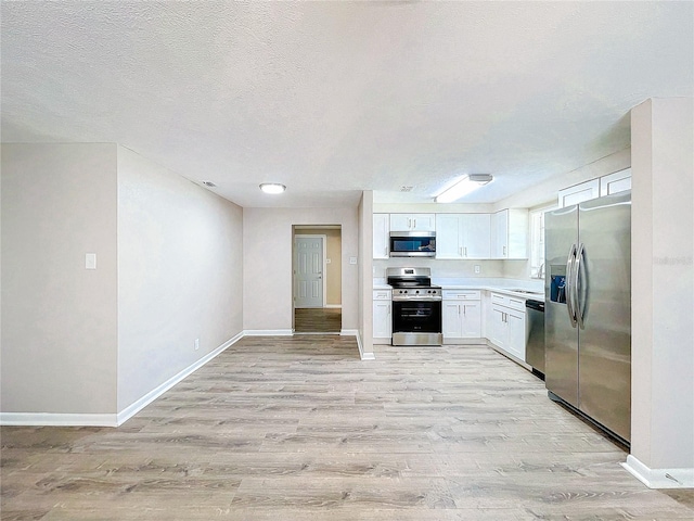 kitchen with white cabinets, appliances with stainless steel finishes, and light hardwood / wood-style flooring