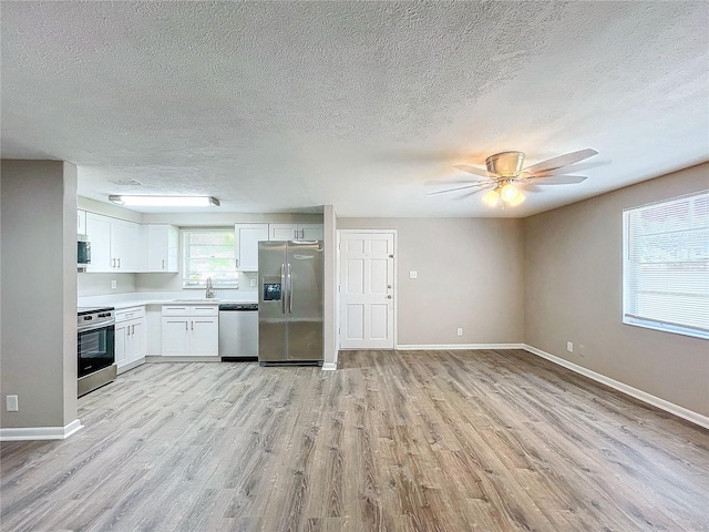 kitchen featuring light wood-type flooring, sink, white cabinets, appliances with stainless steel finishes, and ceiling fan