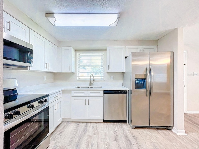 kitchen featuring appliances with stainless steel finishes, light hardwood / wood-style floors, sink, and white cabinets