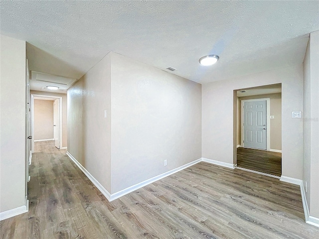 spare room featuring a textured ceiling and hardwood / wood-style flooring