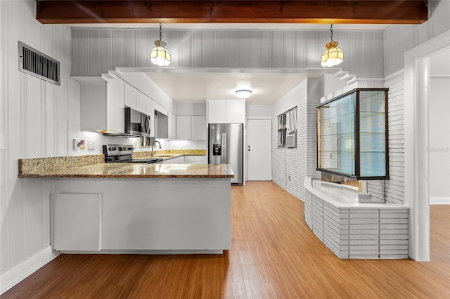 kitchen featuring beamed ceiling, white cabinetry, pendant lighting, and stainless steel appliances