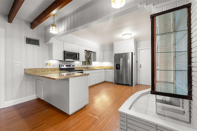 kitchen featuring pendant lighting, beamed ceiling, kitchen peninsula, white cabinetry, and stainless steel appliances