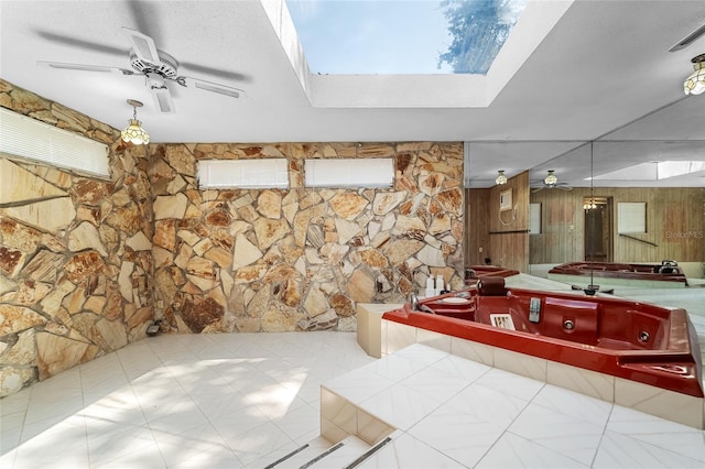 bathroom featuring a tub to relax in, ceiling fan, and a skylight