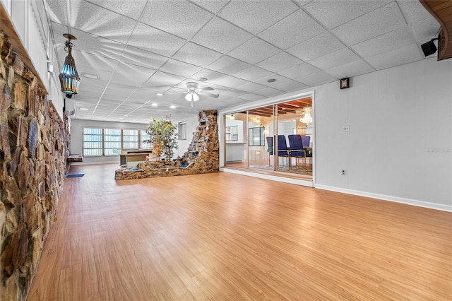 unfurnished living room with a drop ceiling, ceiling fan, and hardwood / wood-style flooring