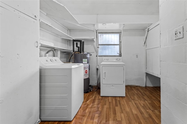 laundry area featuring water heater, hardwood / wood-style flooring, and washer and dryer