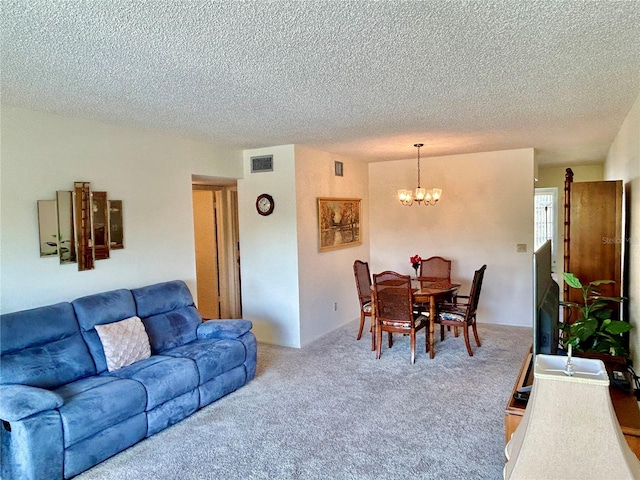 living room featuring carpet floors, a textured ceiling, and a notable chandelier