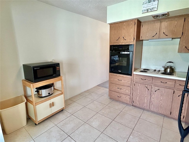 kitchen featuring black appliances, a textured ceiling, and light tile patterned flooring