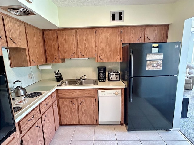 kitchen with black fridge, sink, light tile patterned floors, white dishwasher, and stainless steel cooktop