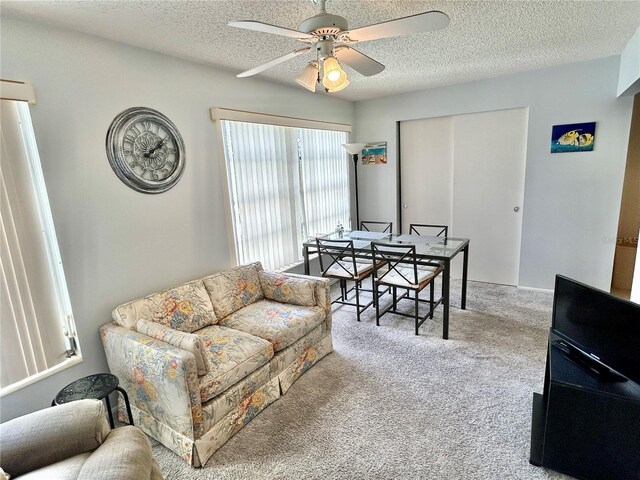 living room with a textured ceiling, ceiling fan, and light colored carpet