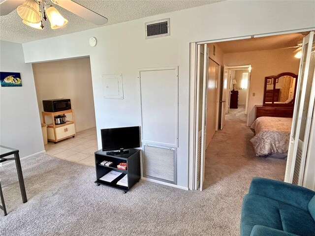 carpeted living room with a textured ceiling and ceiling fan