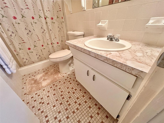 bathroom with tile walls, curtained shower, vanity, tile patterned flooring, and toilet