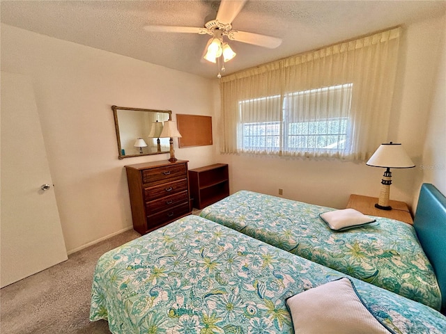 bedroom with ceiling fan, carpet floors, and a textured ceiling