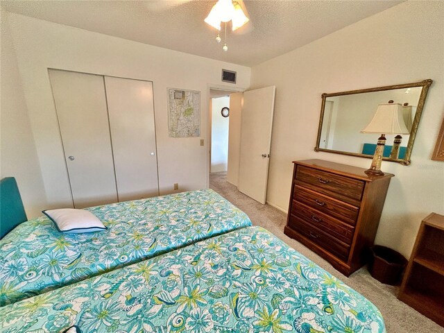 carpeted bedroom featuring a closet, ceiling fan, and a textured ceiling