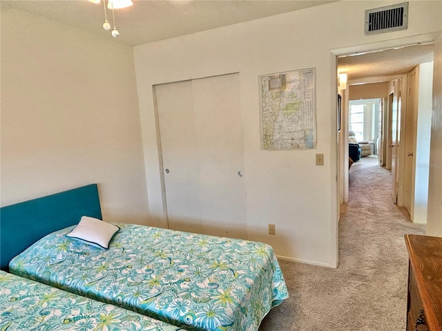 carpeted bedroom with a textured ceiling and a closet