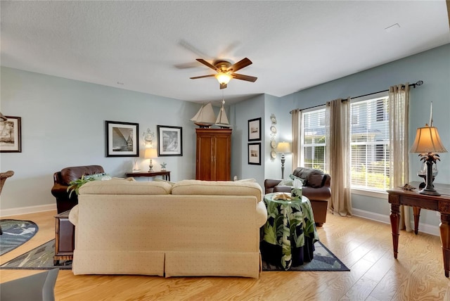 living room featuring ceiling fan, a textured ceiling, and light wood-type flooring