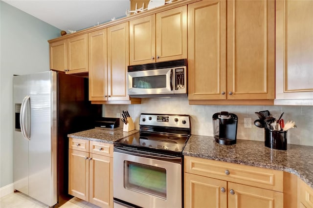 kitchen with appliances with stainless steel finishes, light brown cabinetry, backsplash, and dark stone countertops