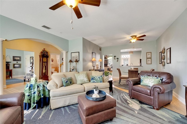 living room with decorative columns, carpet flooring, and ceiling fan