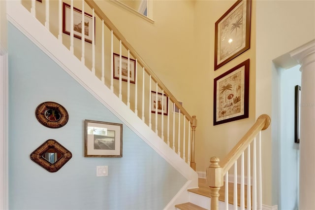 stairway featuring ornate columns and a towering ceiling