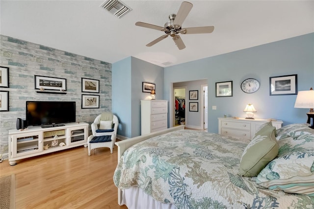 bedroom with light hardwood / wood-style floors, a spacious closet, ceiling fan, and a closet