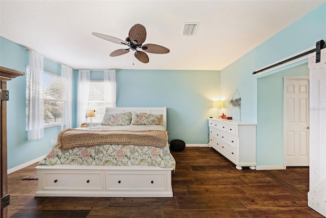 bedroom featuring ceiling fan, dark hardwood / wood-style floors, and a barn door