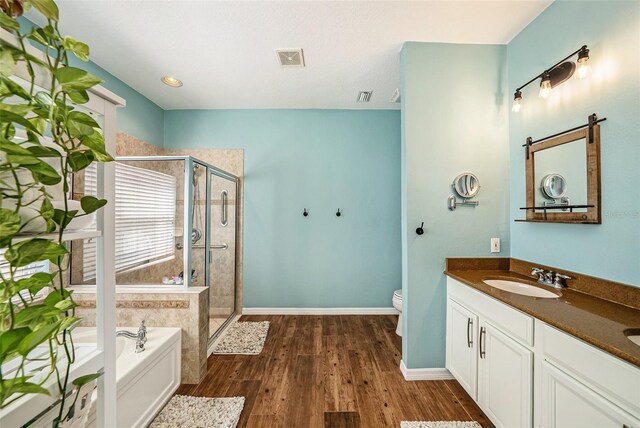 full bathroom featuring wood-type flooring, shower with separate bathtub, vanity, and toilet