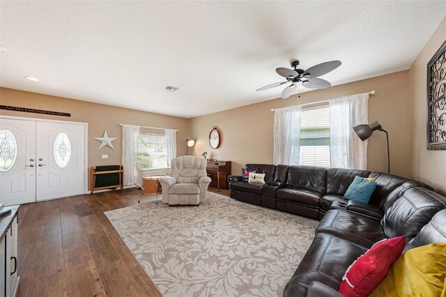 living room featuring a textured ceiling, dark hardwood / wood-style flooring, and ceiling fan