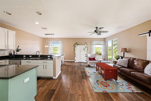 kitchen with a wealth of natural light, white cabinetry, sink, and decorative light fixtures