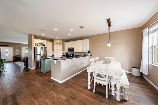 kitchen featuring pendant lighting, dark wood-type flooring, appliances with stainless steel finishes, and a healthy amount of sunlight