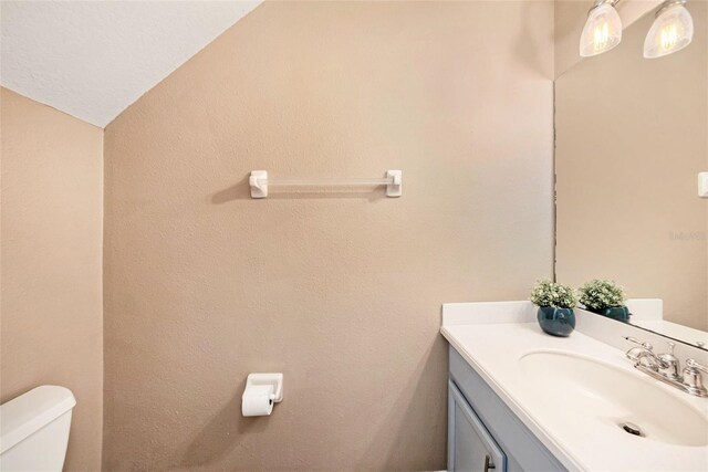 bathroom with vanity, toilet, and vaulted ceiling