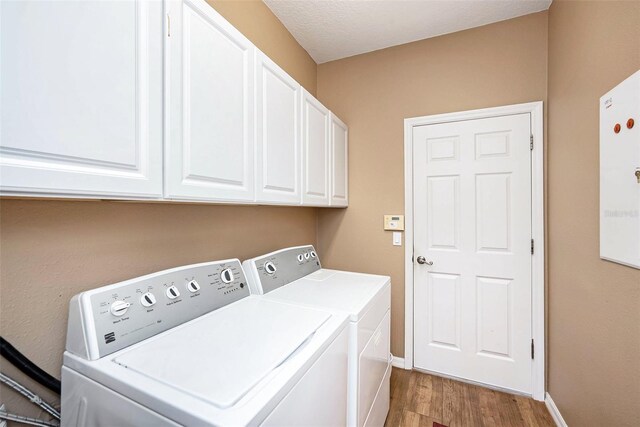 washroom featuring cabinets, separate washer and dryer, hardwood / wood-style flooring, and a textured ceiling