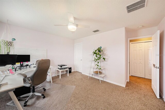 carpeted office with a textured ceiling and ceiling fan