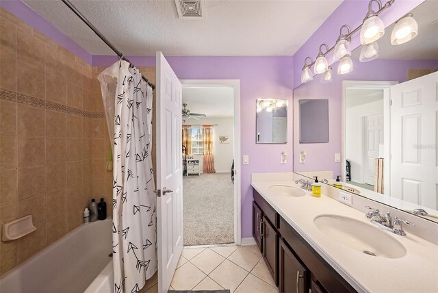 bathroom featuring a textured ceiling, shower / tub combo with curtain, vanity, and tile patterned flooring