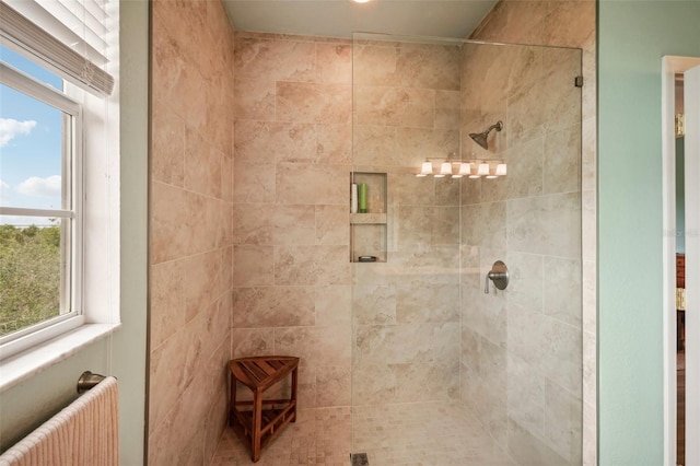 bathroom featuring a shower with door, radiator heating unit, and a wealth of natural light