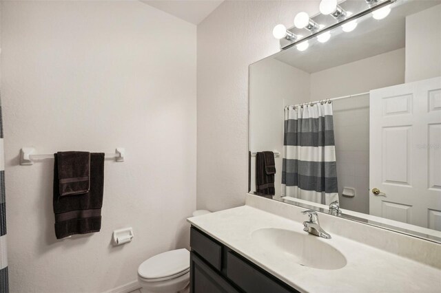 bathroom with curtained shower, vanity, and toilet