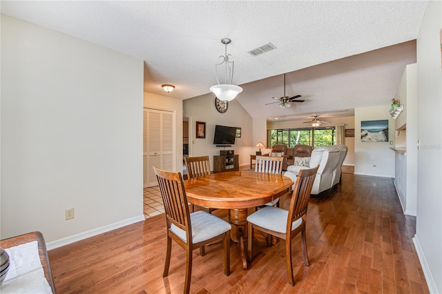 dining space featuring ceiling fan, hardwood / wood-style flooring, a textured ceiling, and vaulted ceiling