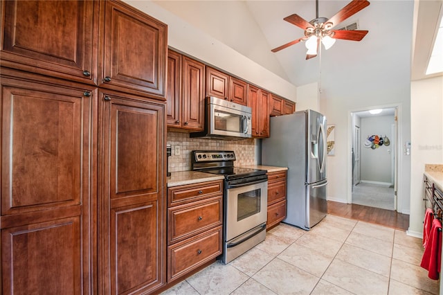 kitchen with appliances with stainless steel finishes, backsplash, ceiling fan, high vaulted ceiling, and light tile patterned floors