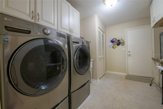 laundry area with independent washer and dryer, a textured ceiling, and cabinets